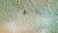 Young girl enjoying a beautiful beach shoreline. Crystal clear ocean water, downward view from drone