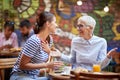 A young girl is enjoying a company of her older female friend while the have a drink at a bar. Leisure, bar, friendship, outdoor