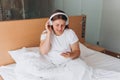 Young girl enjoying music with wireless headphones, she relaxing in cozy bedroom at home. Enjoy good quality sound Royalty Free Stock Photo