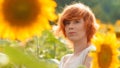 Young girl enjoying nature on the field of sunflowers at sunset, portrait of the beautiful redheaded woman girl with a sunflowers Royalty Free Stock Photo