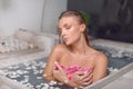 Young girl enjoys spa treatments in the bathroom with flowers Royalty Free Stock Photo