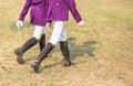 Young girl equestrians in professional apparel dressage purple jacket walking in th Royalty Free Stock Photo