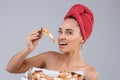 A girl holding a mouthful of appetizing piece of pizza. On a gray background.