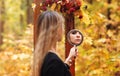 Young girl with evening makeup wearing black witch costume looking in mirror in autumn forest Royalty Free Stock Photo