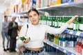 Young girl examining labels on bottles of soju in Asian store