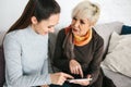 A young girl explains to an elderly woman how to use a tablet or shows some application or teaches you how to use a