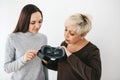 A young girl explains to an elderly woman how to use virtual reality glasses. The older generation and new technologies.