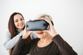 A young girl explains to an elderly woman how to use virtual reality glasses. The older generation and new technologies. Royalty Free Stock Photo