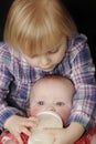 Young girl feeding baby sister