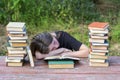 Young girl fell asleep after reading books on a wooden table in the garden Royalty Free Stock Photo