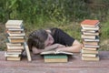 Young girl fell asleep after reading books on a wooden table in the garden Royalty Free Stock Photo