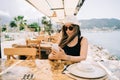 Young girl female lady in sunglasses looking at her mobile smart phone gadget in a street seaside cafe restaurant coffee