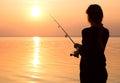 Young girl fishing at sunset near the sea Royalty Free Stock Photo