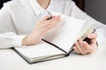 A young girl flips through the pages in a notebook, a pen in her hand