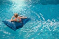 Young girl on floating bean bag relaxing in swimming pool Royalty Free Stock Photo