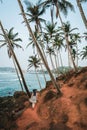 Young girl in a flowy dress walking away at the Coconut Tree Hill landmark near Mirissa beach. Palm trees growing diagonally all Royalty Free Stock Photo