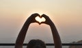 A young girl formed heart bya young girl formed heart by her fingers on the sunset background