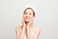 Young girl with fresh and clean skin, wearing white bath towel on her head, touching her face, looking with cute smile against Royalty Free Stock Photo