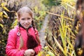 The young girl with a frightened face stands among the abandoned garden