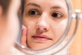Young girl in front of a bathroom mirror putting cream on a red pimple. Beauty skincare and wellness morning concept Royalty Free Stock Photo