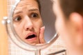 Young girl in front of a bathroom mirror putting cream on a red pimple. Beauty skincare and wellness morning concept Royalty Free Stock Photo