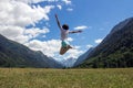 The young girl full of joy jumps against the background of mountains