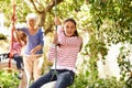 Young girl, garden and grandma playing with grandkid on background or holidays, having fun on a tyre swing in summer Royalty Free Stock Photo