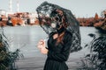 Young girl in a gas mask in a red dress with a book in her hands against the background of smoking factory chimneys