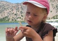 Beautiful blond little girl in a pink hat observing an ear of wheat. Royalty Free Stock Photo