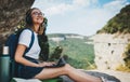 Young girl with glasses and backpack enjoying summer vacation in mount listen music in headphones and laptop in nature Royalty Free Stock Photo