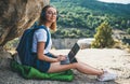 Young girl with glasses and backpack enjoying vacation in mount using headphones and laptop in nature, traveler woman planning Royalty Free Stock Photo