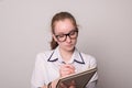 Young girl in glasses makes notes in a notebook. Cute young girl secretary with glasses