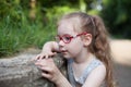 young girl with glasses playing in the park with stones and insects