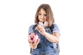 Young girl in glasses puts a coin into a piggybank Royalty Free Stock Photo