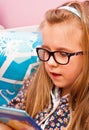 Young girl with glasses reading in bed Royalty Free Stock Photo