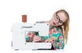 Young girl with glasses sews on a sewing machine, isolated on white background