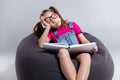 Young girl in glasses sleeping with a book on a gray bean bag Royalty Free Stock Photo
