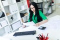 A young girl in glasses works in the office with a computer and a calculator looks through the documents. Royalty Free Stock Photo