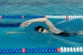 Young girl in goggles and cap swimming crawl stroke style in the blue water pool. Royalty Free Stock Photo