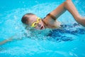 Young girl in goggles and cap swimming crawl stroke style Royalty Free Stock Photo