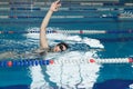 Young girl in goggles and cap swimming crawl stroke style in the blue water pool. Royalty Free Stock Photo