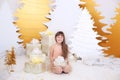 Young girl in golden dress laughs and enjoys gift. Little girl opening magical christmas present at home. child holds christmas pr Royalty Free Stock Photo