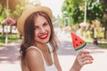 Young girl in good mood walks in the park and smiles. Sweet happy girl in straw hat walks in the park with a lollipop in the form