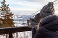 A young girl in a gray knitted hat looks through stationary binoculars on an observation deck in the alatai mountains in winter Royalty Free Stock Photo