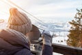 A young girl in a gray knitted hat looks through stationary binoculars on an observation deck in the alatai mountains in winter Royalty Free Stock Photo