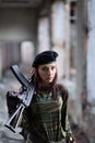 A young girl with a green camouflage uniform and a black beret with a gun among the ruins. Girl warrior with weapons Royalty Free Stock Photo