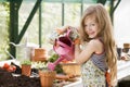 Young girl in greenhouse watering potted plant