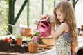 Young girl in greenhouse watering potted plant