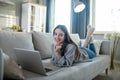 Young girl in a grey sweater laying on the sofa and chatting online
