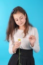 Young girl guesses on a chamomile flower. Young girl tears off petals of daisy.